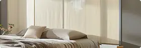 Zugezogene blickdichte Flächenvorhänge in Beige hängend hinter einem Bett im Schlafzimmer